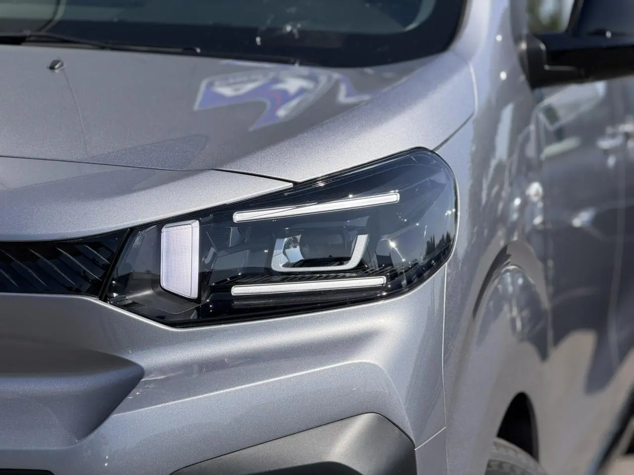 Gros plan sur le phare avant droit du Citroën Jumpy gris Artense, mettant en valeur son design LED moderne.