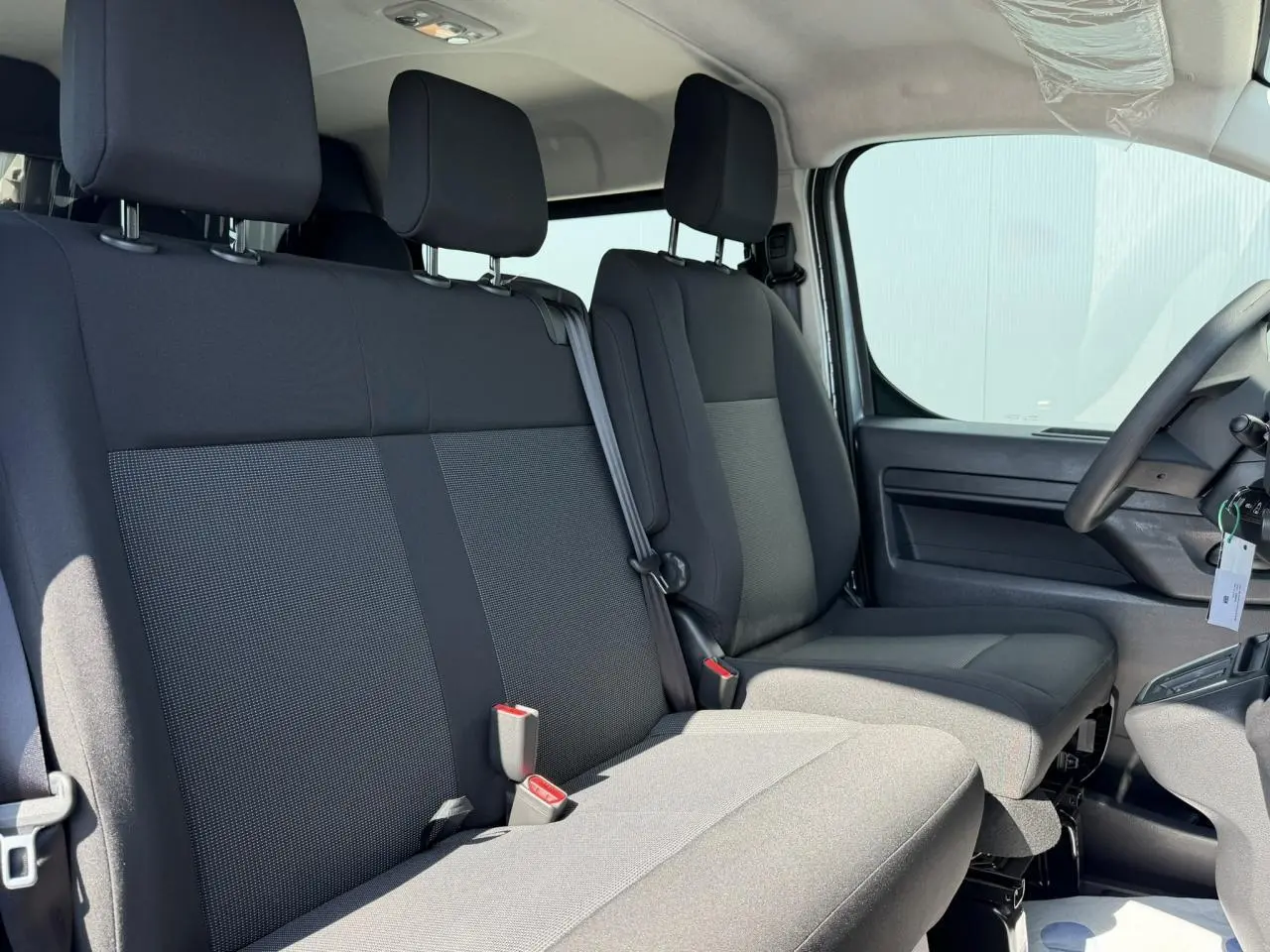 Vue intérieure côté droit montrant les sièges avant et banquette 3 places du Citroën Jumpy gris Artense.