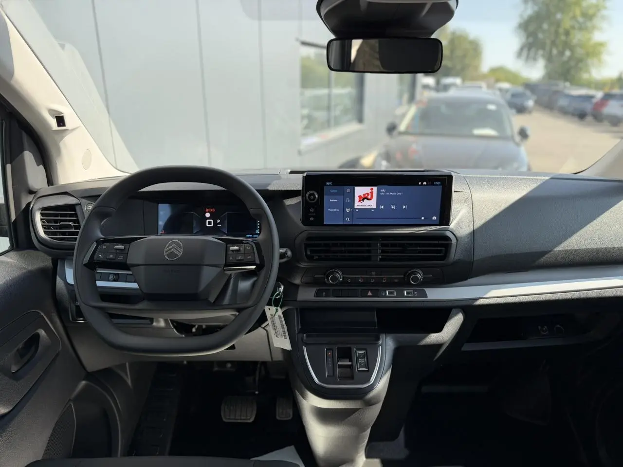 Vue intérieure avant du Citroën Jumpy gris Artense, tableau de bord avec écran tactile 10 pouces et volant multifonction.