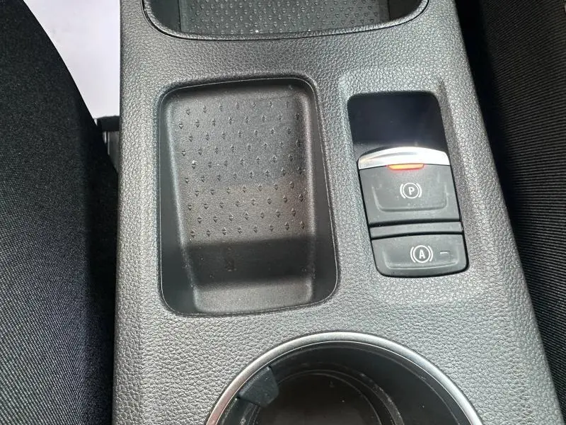 Gros plan sur la console centrale noire du Renault Symbioz 2025, avec bouton de frein à main électronique et rangement adjacent.