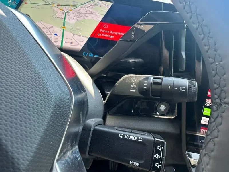 Détail intérieur du Renault Austral 2025 montrant la commande d’essuie-glace et le levier de vitesses sur colonne, avec écran tactile en arrière-plan.
