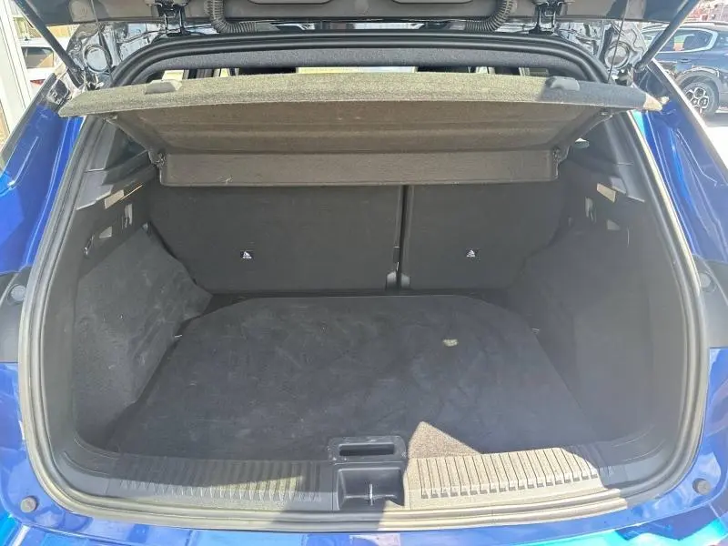Coffre ouvert vu de l'arrière d'un Renault Austral 2025 bleu Iron avec intérieur noir et cache-bagages relevé.