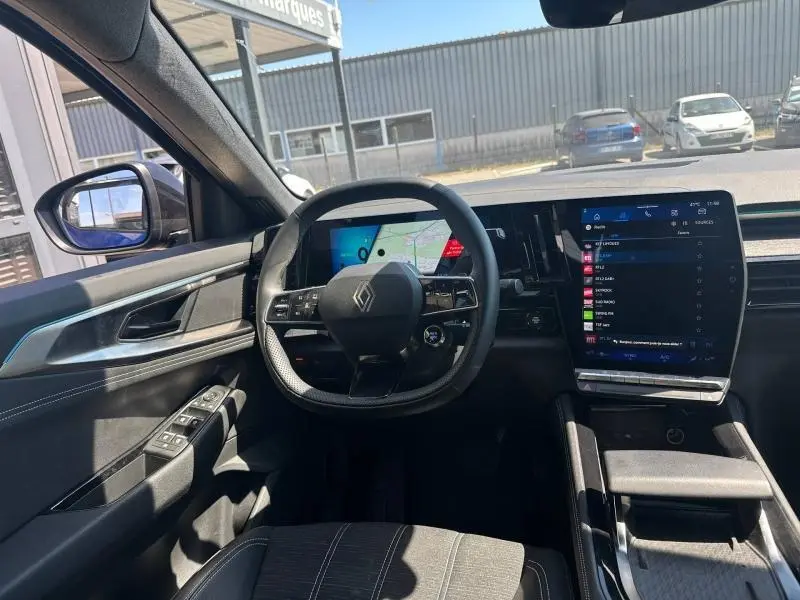 Vue intérieure avant du Renault Austral 2025, volant multifonction, écran tactile vertical et sellerie gris dégradé.