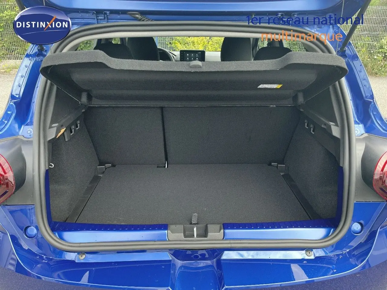 Coffre ouvert d'une Dacia Sandero Stepway 2024 bleu iron metal, vue arrière montrant l'espace de chargement vide.