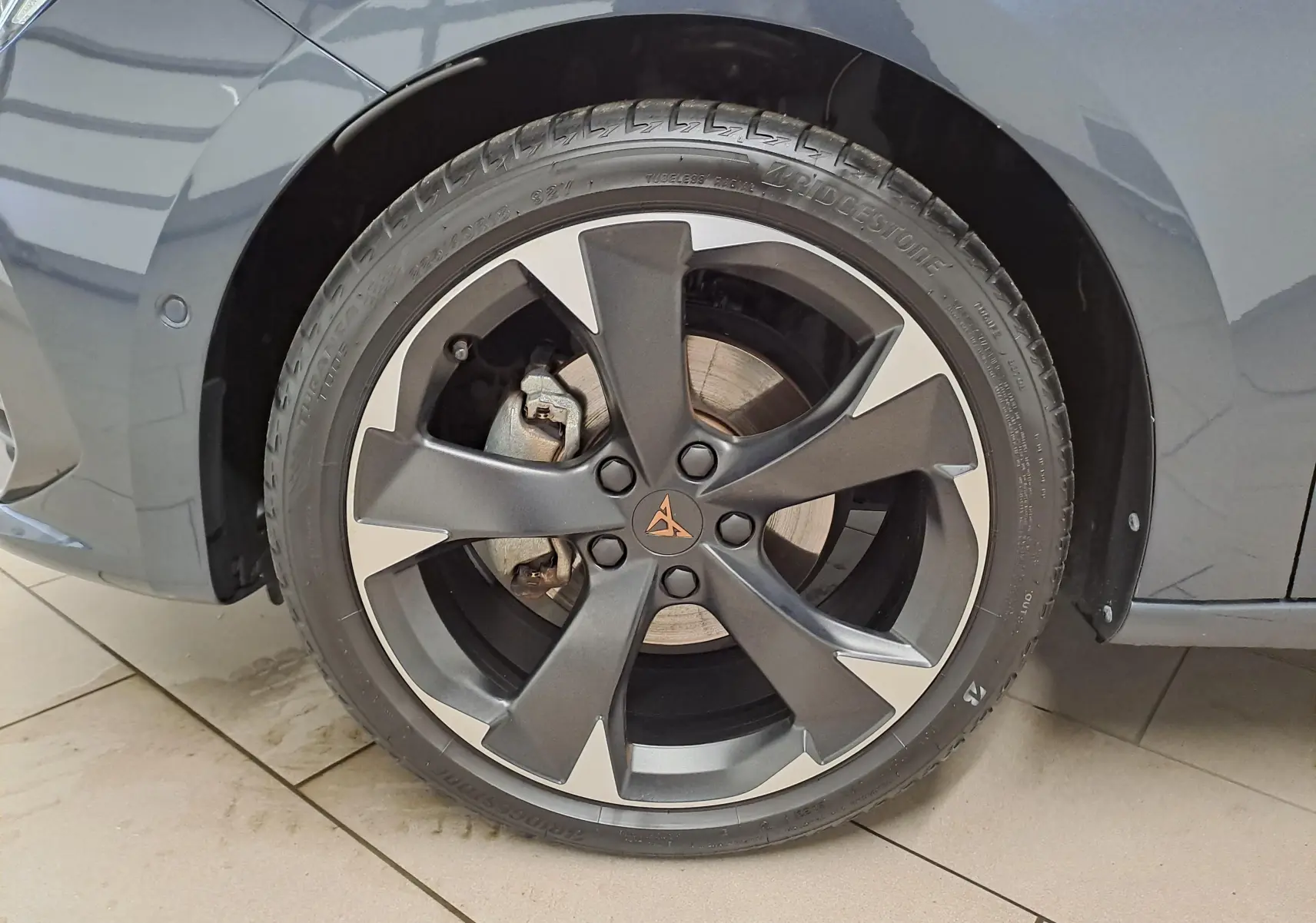 Gros plan sur la roue avant gauche de la CUPRA Leon 2023 en gris magnétique avec jante alliage bicolore distinctive.