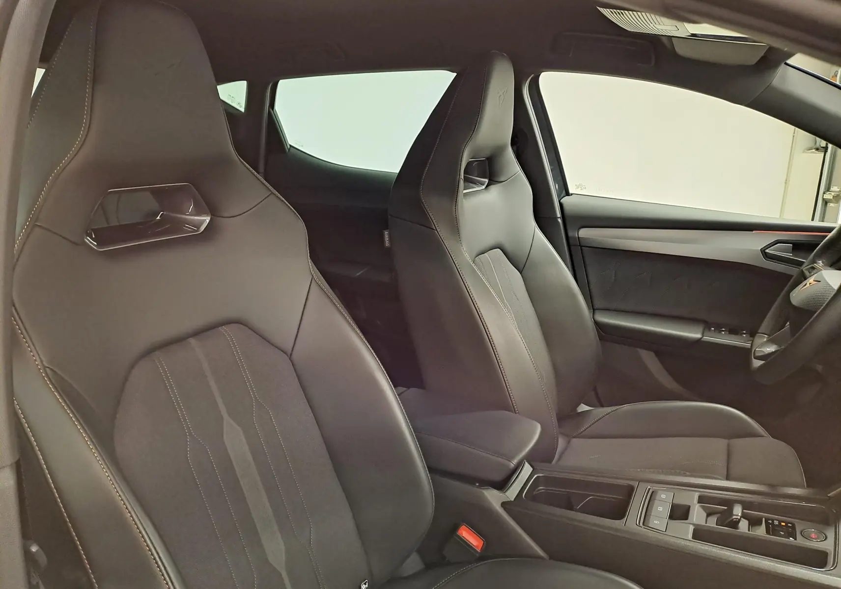 Intérieur de la CUPRA Leon 2023, vue latérale des sièges avant sport en cuir noir avec surpiqûres contrastées.