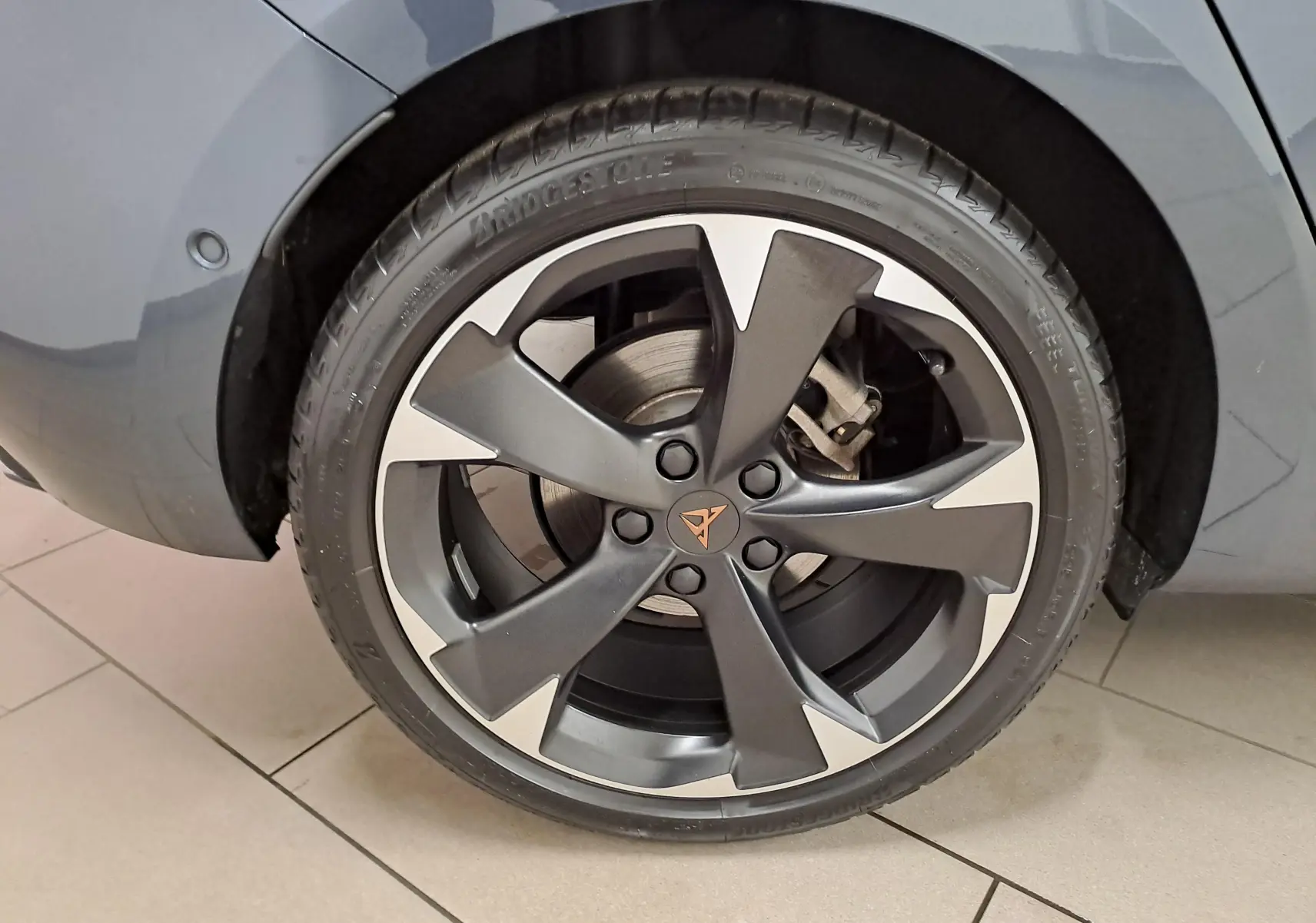 Gros plan sur la roue avant droite d'une CUPRA Leon 2023 gris magnétique avec jante alliage noire et argentée distinctive.