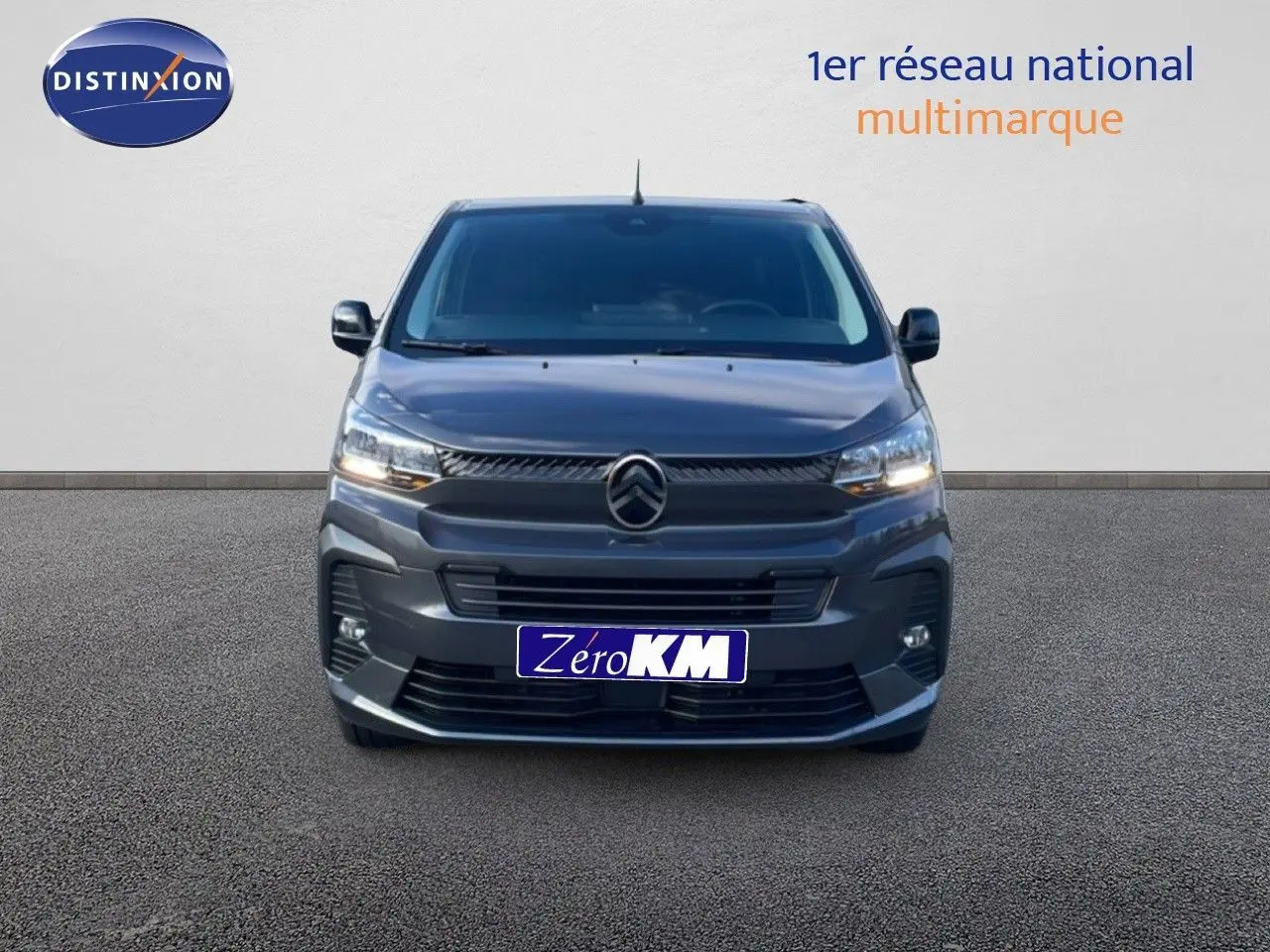 Vue frontale d'un Citroën Jumpy Van Long L3 gris titane métal avec calandre et phares allumés sur fond neutre.