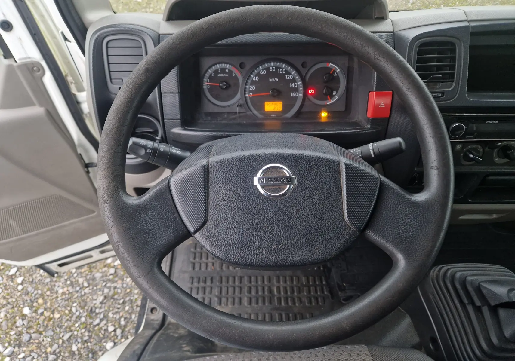 Vue intérieure centrée sur le volant noir du Nissan Cabstar 2010, avec tableau de bord et levier de vitesses manuelle visibles.