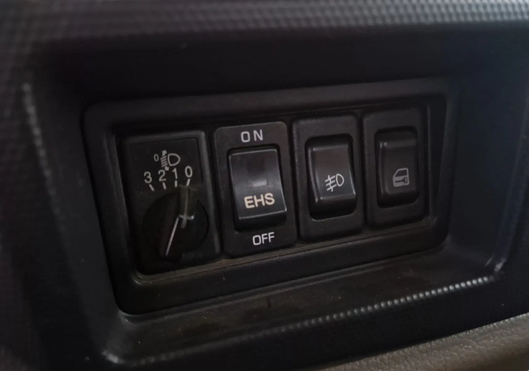 Gros plan sur les commandes intérieures noires du Nissan Cabstar 2010, avec interrupteurs pour phares et fonctions spécifiques.