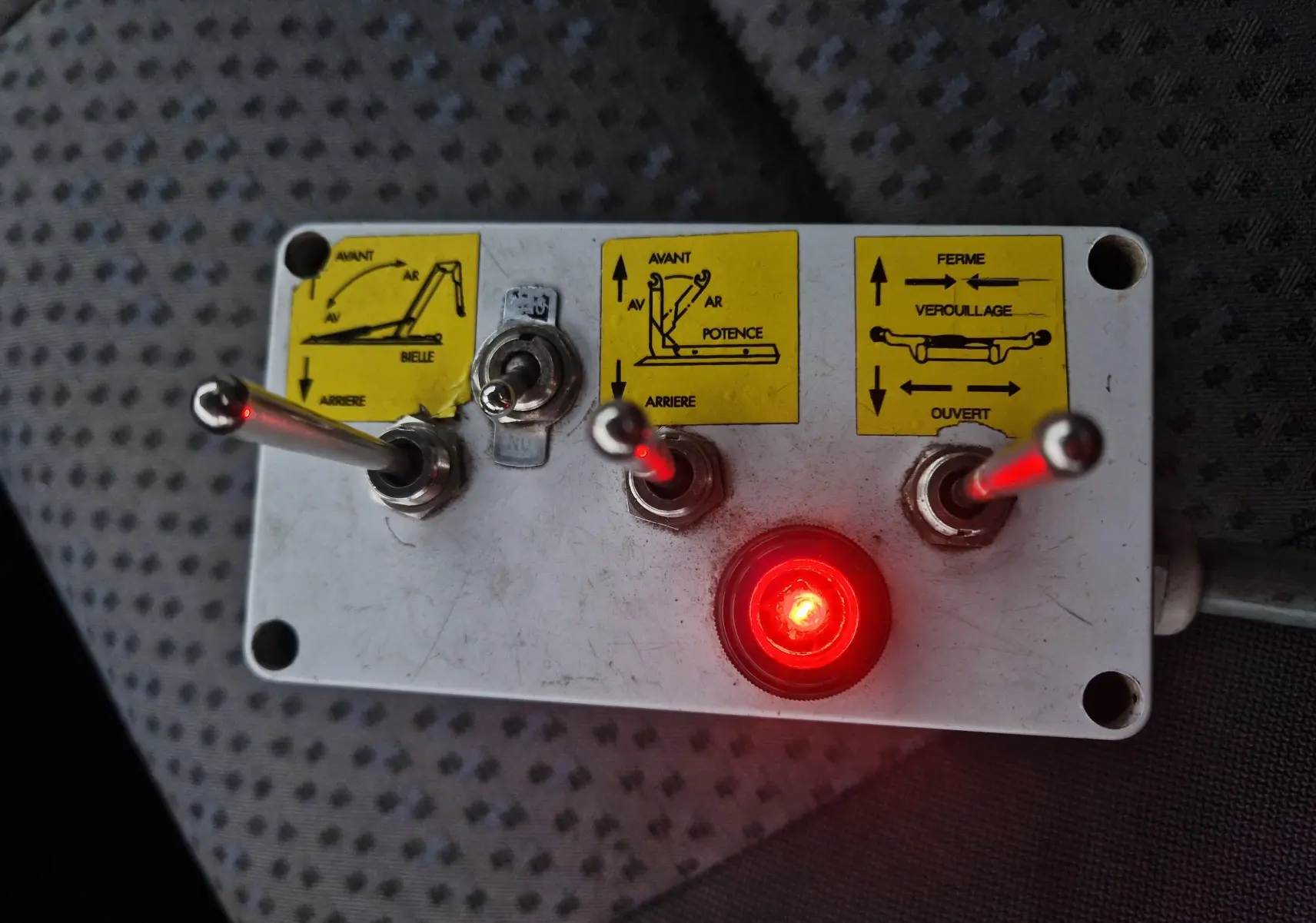 Gros plan sur le boîtier de commande blanc avec leviers et voyants rouges du bras polybenne du Nissan Cabstar blanc.