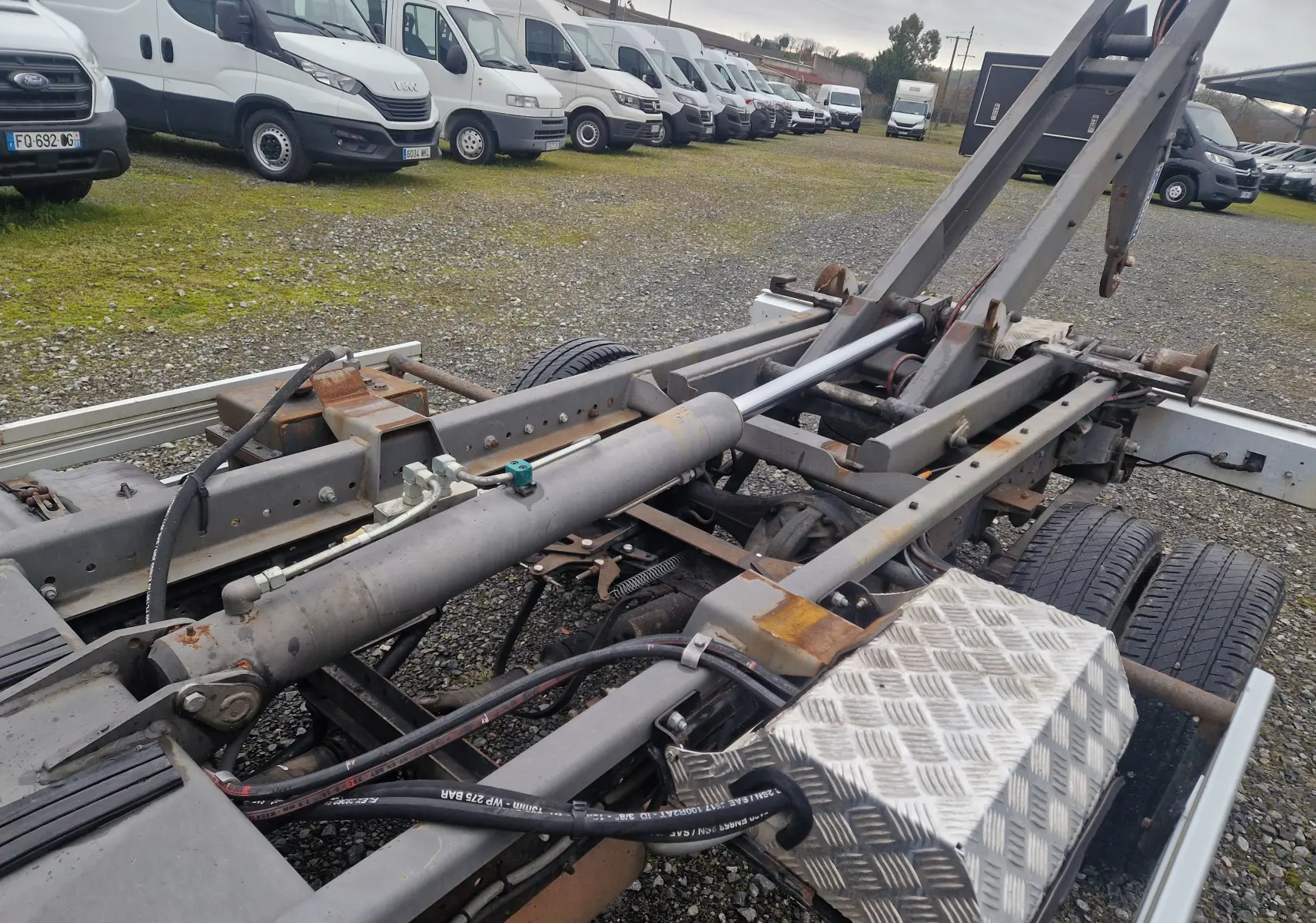 Vue rapprochée du châssis cabine blanc Nissan Cabstar 2010, mettant en valeur le bras polybenne et la structure arrière.