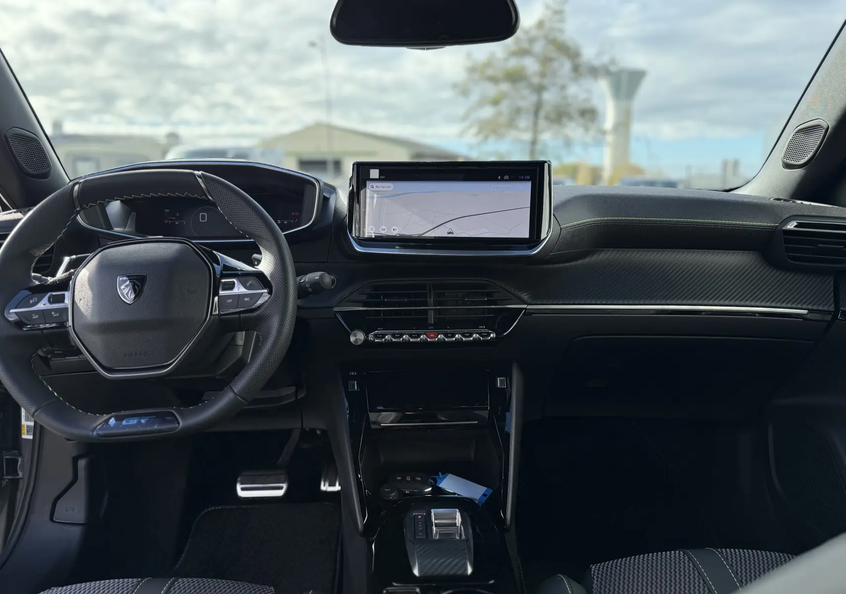 Vue intérieure avant du Peugeot 2008 Hybrid 145ch GT 2025, tableau de bord noir avec écran tactile central et volant compact.