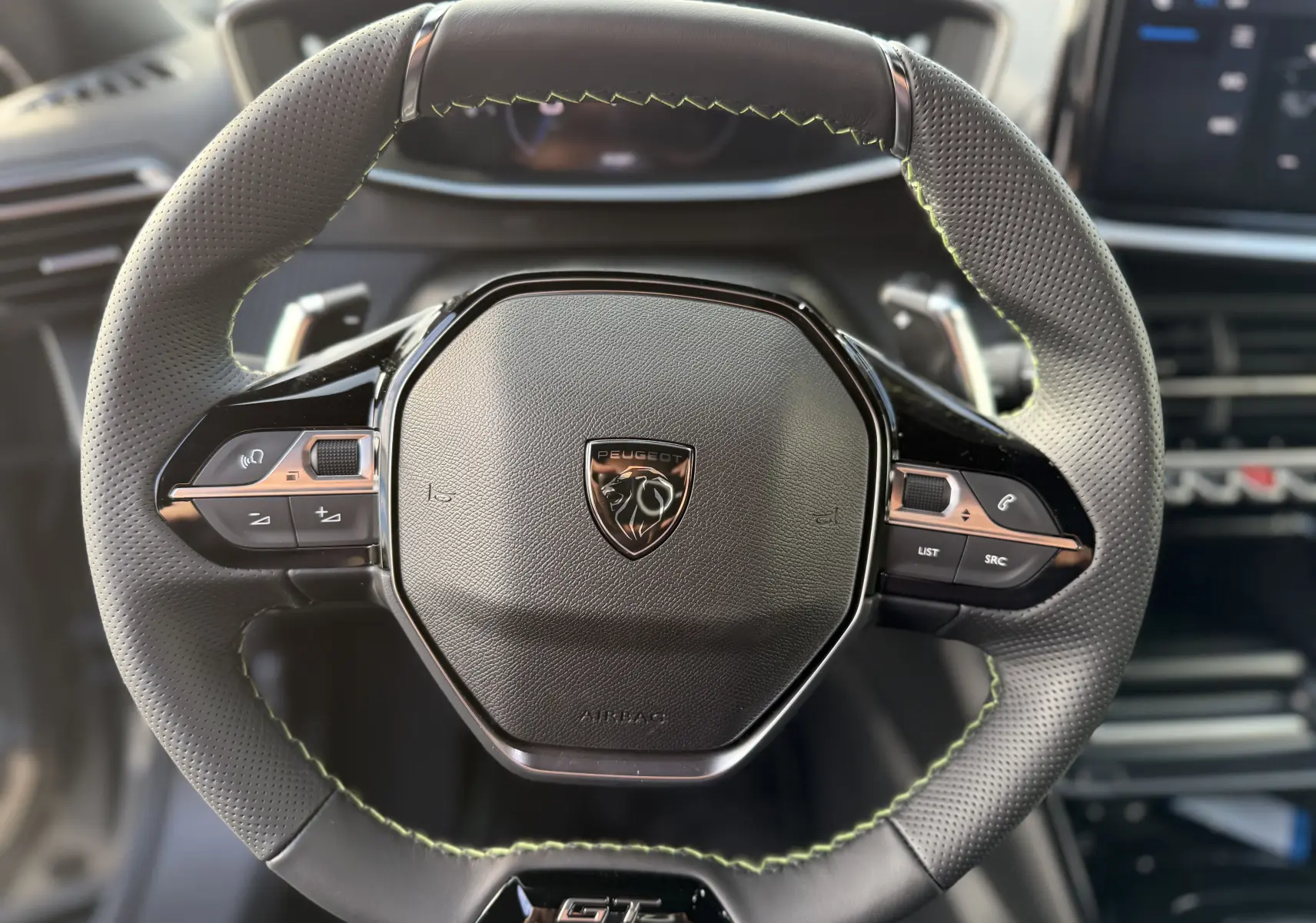 Vue rapprochée du volant cuir perforé avec coutures vertes et logo Peugeot du SUV 2008 Hybrid 145ch GT 2025.