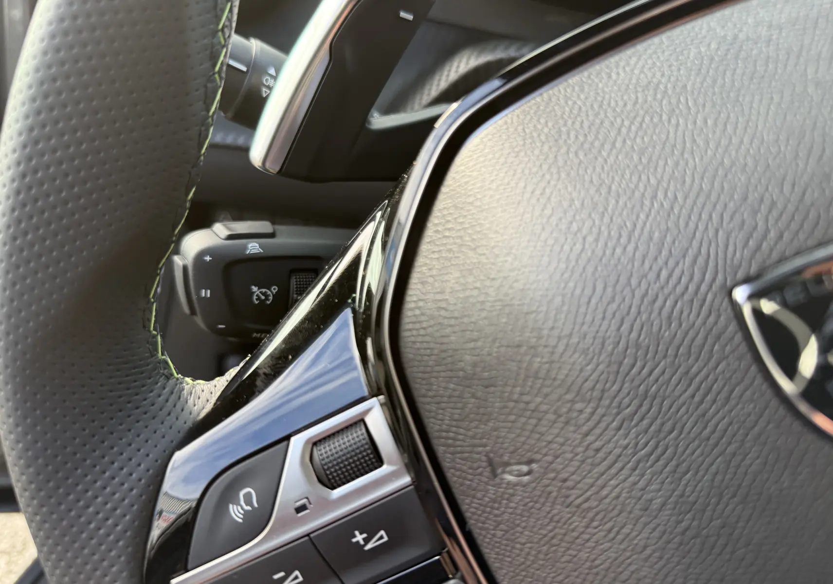 Gros plan sur le volant en cuir perforé du Peugeot 2008 Hybrid 145ch GT, mettant en valeur les commandes intégrées.