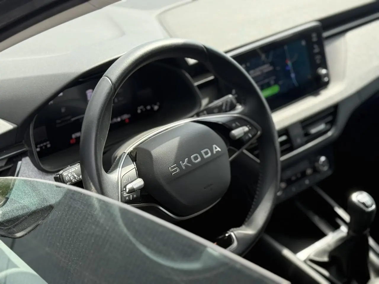 Intérieur de la Skoda Scala TSI 116 gris graphite, vue rapprochée du volant cuir multifonctions et levier de vitesse manuel.