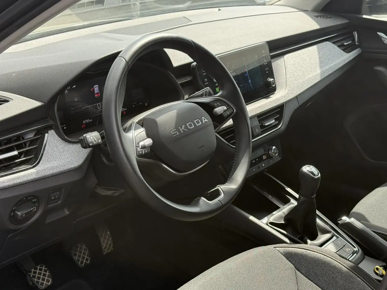 Vue intérieure côté conducteur du Skoda Scala TSI 116 gris graphite, volant cuir et levier de vitesses manuel visibles.