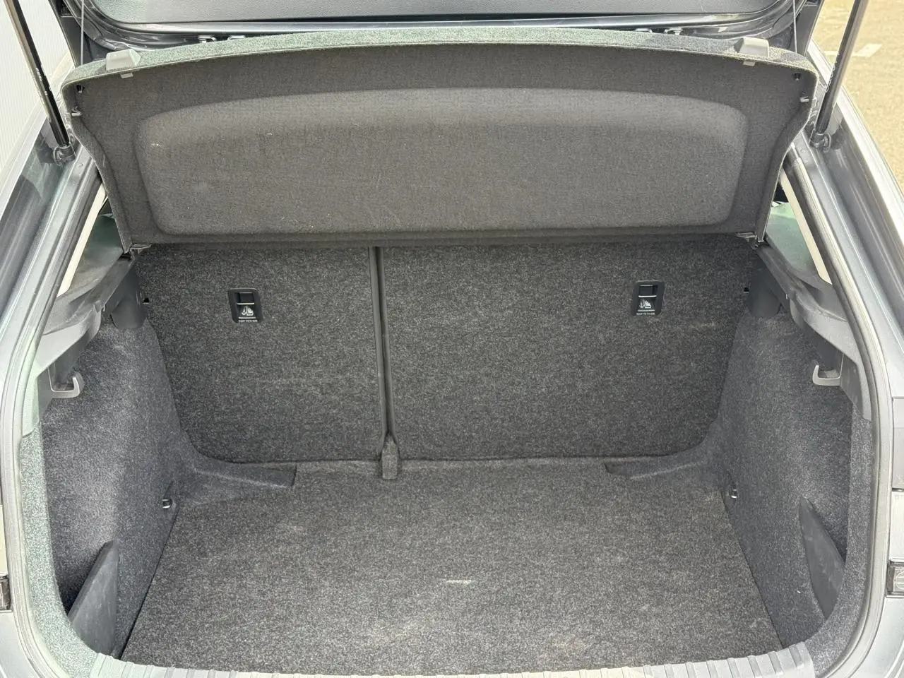 Coffre ouvert d'une Skoda Scala TSI 116 gris graphite, vue de l'arrière montrant l'espace de chargement vide.
