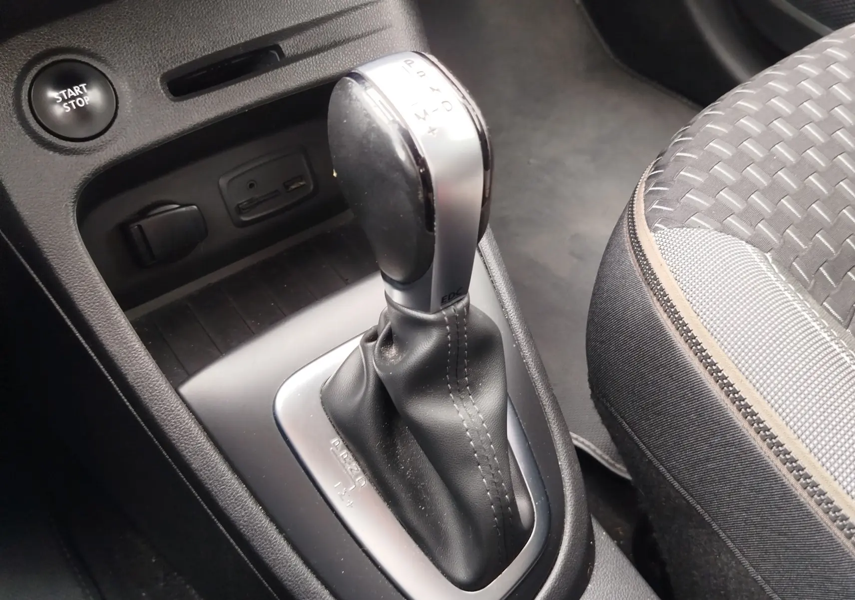 Le levier de vitesse automatique de la Renault Captur 2018 en gros plan, avec bouton Start/Stop et siège tissu gris.