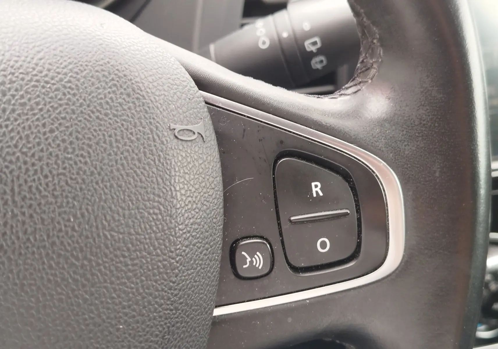 Gros plan sur les commandes noires du volant en cuir noir du Renault Captur 2018, boutons R et O visibles.