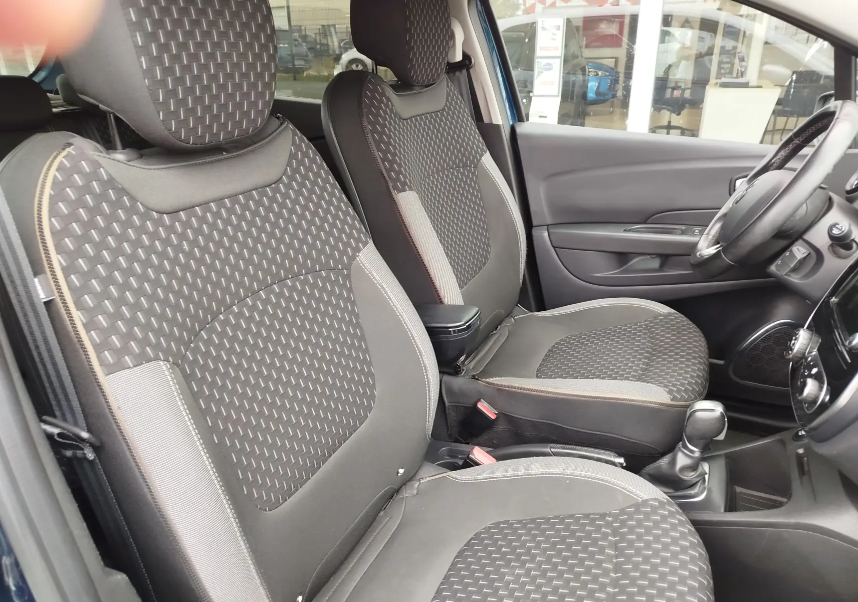 Vue intérieure côté droit du Renault Captur 2018, sièges avant gris à motifs tissés et volant visible.