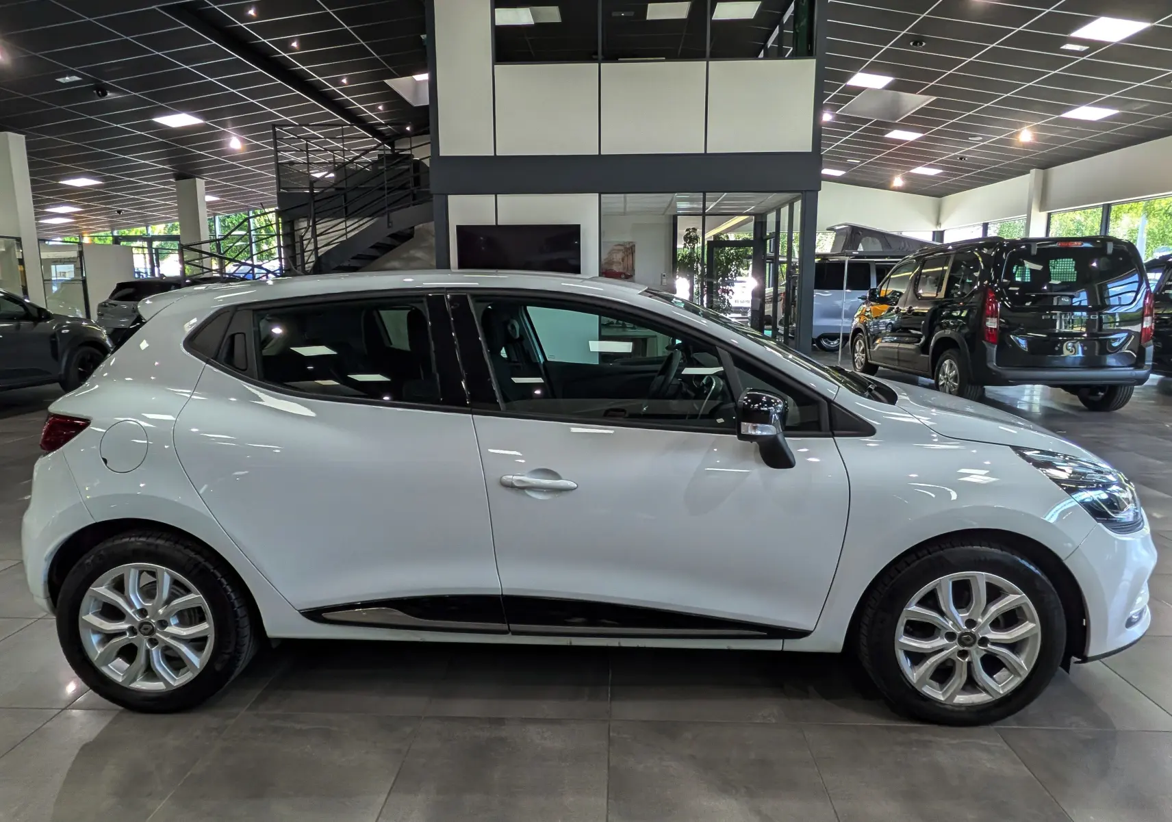 Renault Clio IV TCe 75 blanc glacier vue de profil côté gauche, avec jantes alliage et poignées de porte intégrées.