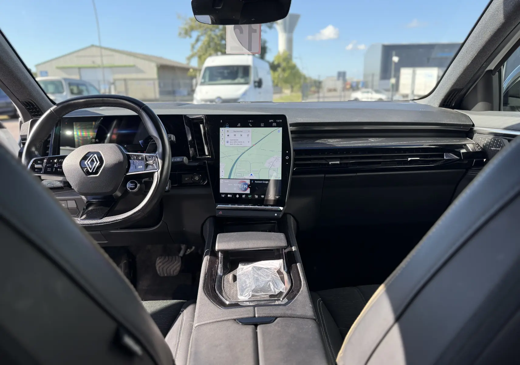 Vue intérieure du Renault Austral 2023 blanc, tableau de bord moderne avec écran tactile central vertical et volant multifonction.