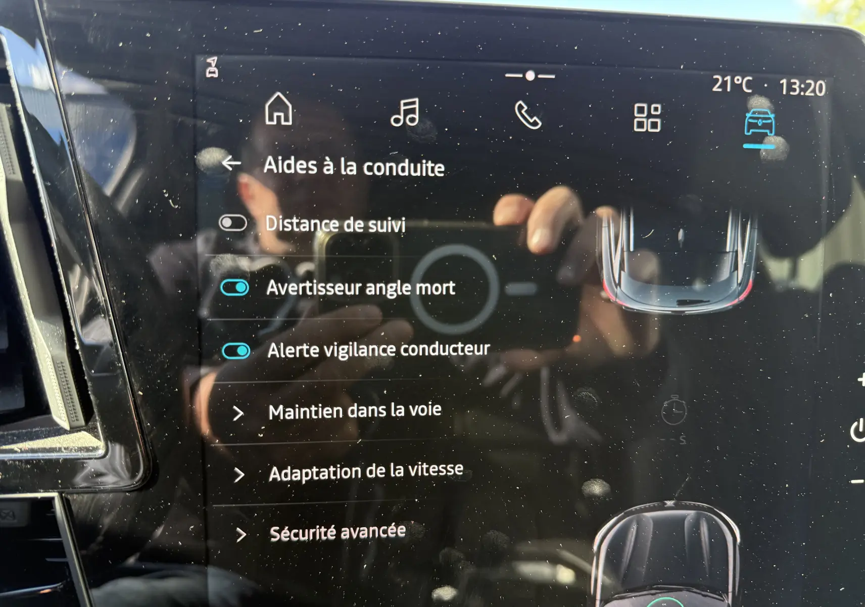 Écran tactile intérieur du Renault Austral 2023 montrant les aides à la conduite activées, avec reflet partiel du conducteur.