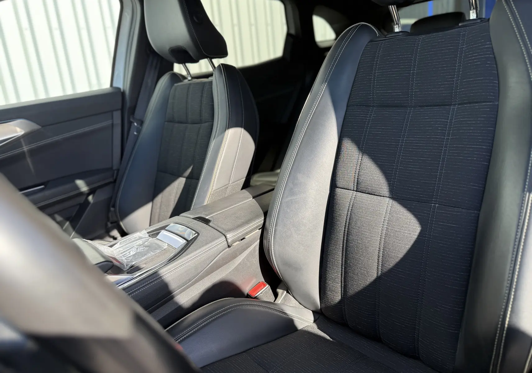 Vue intérieure rapprochée des sièges avant en cuir noir et tissu du Renault Austral 2023, avec console centrale visible.
