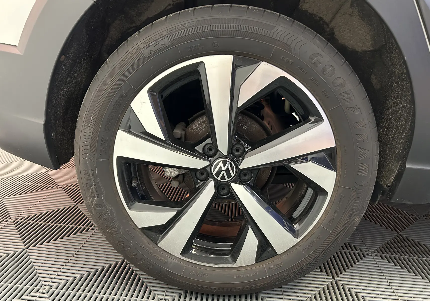 Gros plan sur la roue avant droite d'un Volkswagen Taigo blanc, jante alliage bicolore au design moderne.