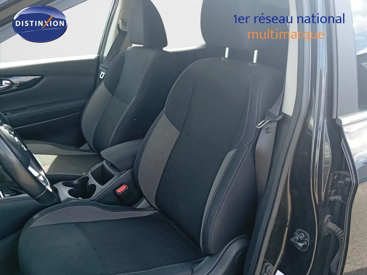 Vue intérieure côté conducteur du Nissan Qashqai noir métal 2018, mettant en valeur les sièges avant en tissu bicolore.