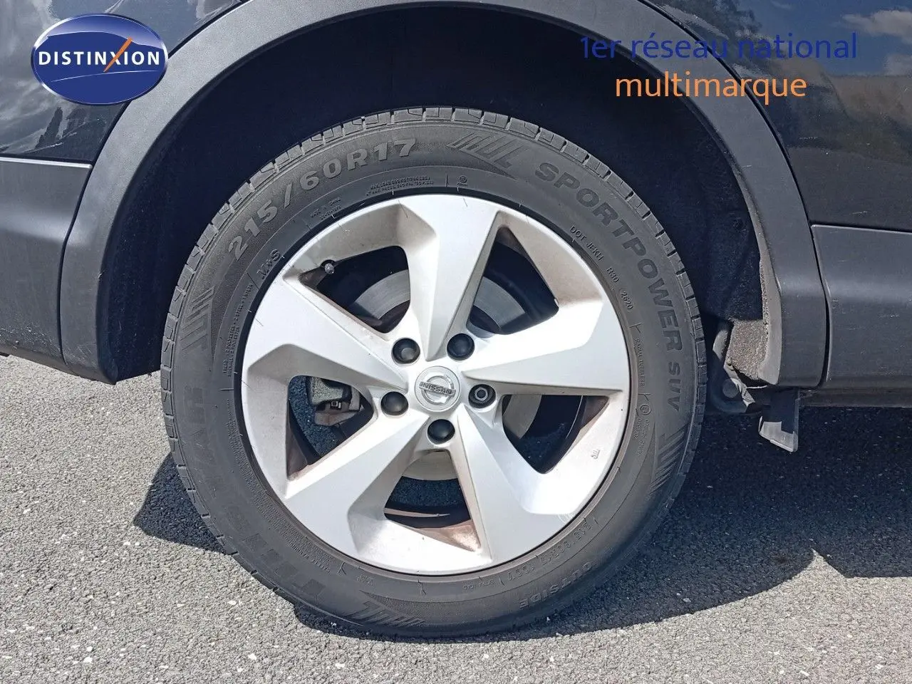 Gros plan sur la roue avant droite d'un Nissan Qashqai noir métal de 2018 avec jante argentée et pneu Sportpower SUV.