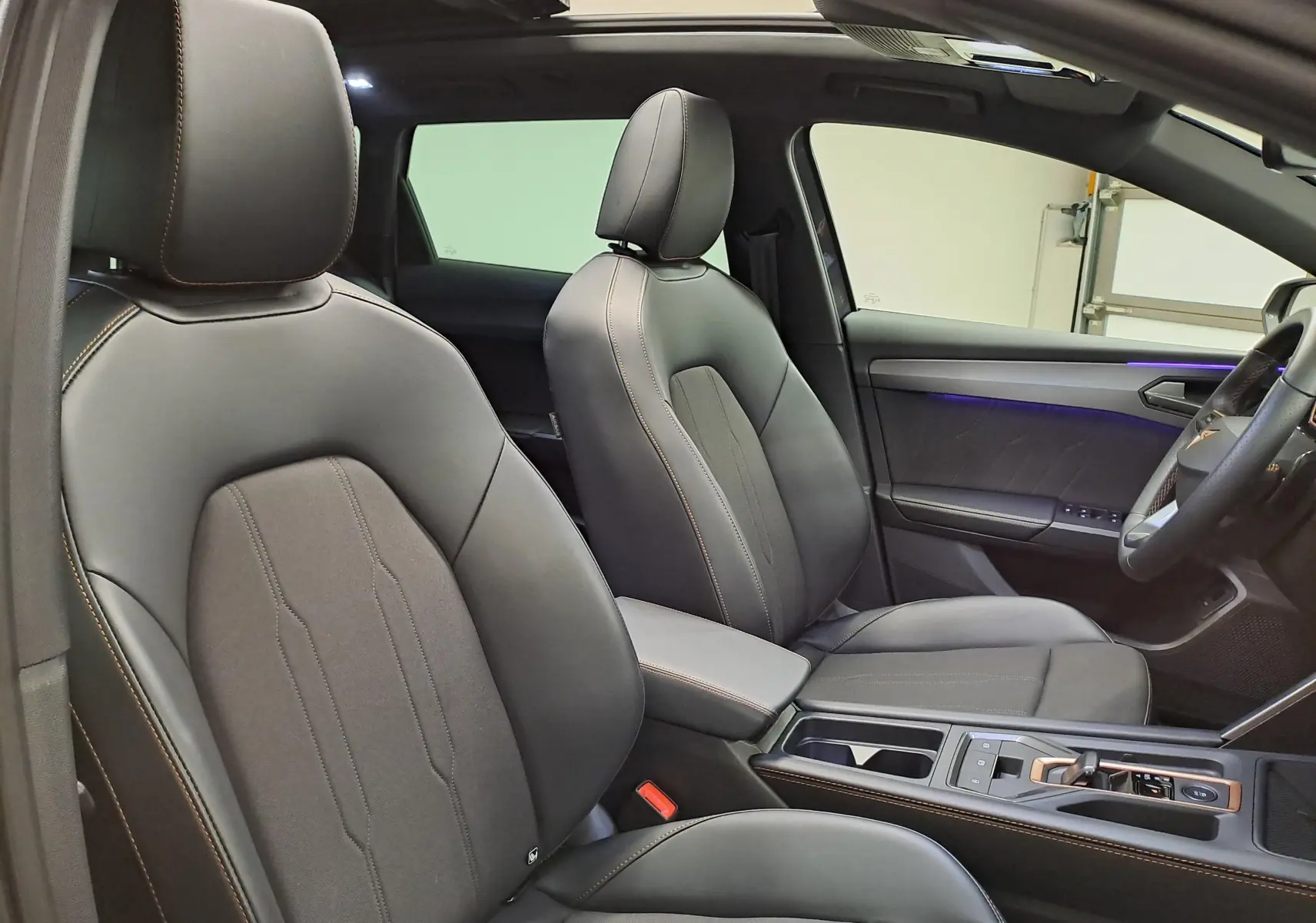 Vue intérieure côté droit de la CUPRA LEON ST 2.0 TDI 150 DSG7 avec sièges cuir noirs et toit ouvrant panoramique.