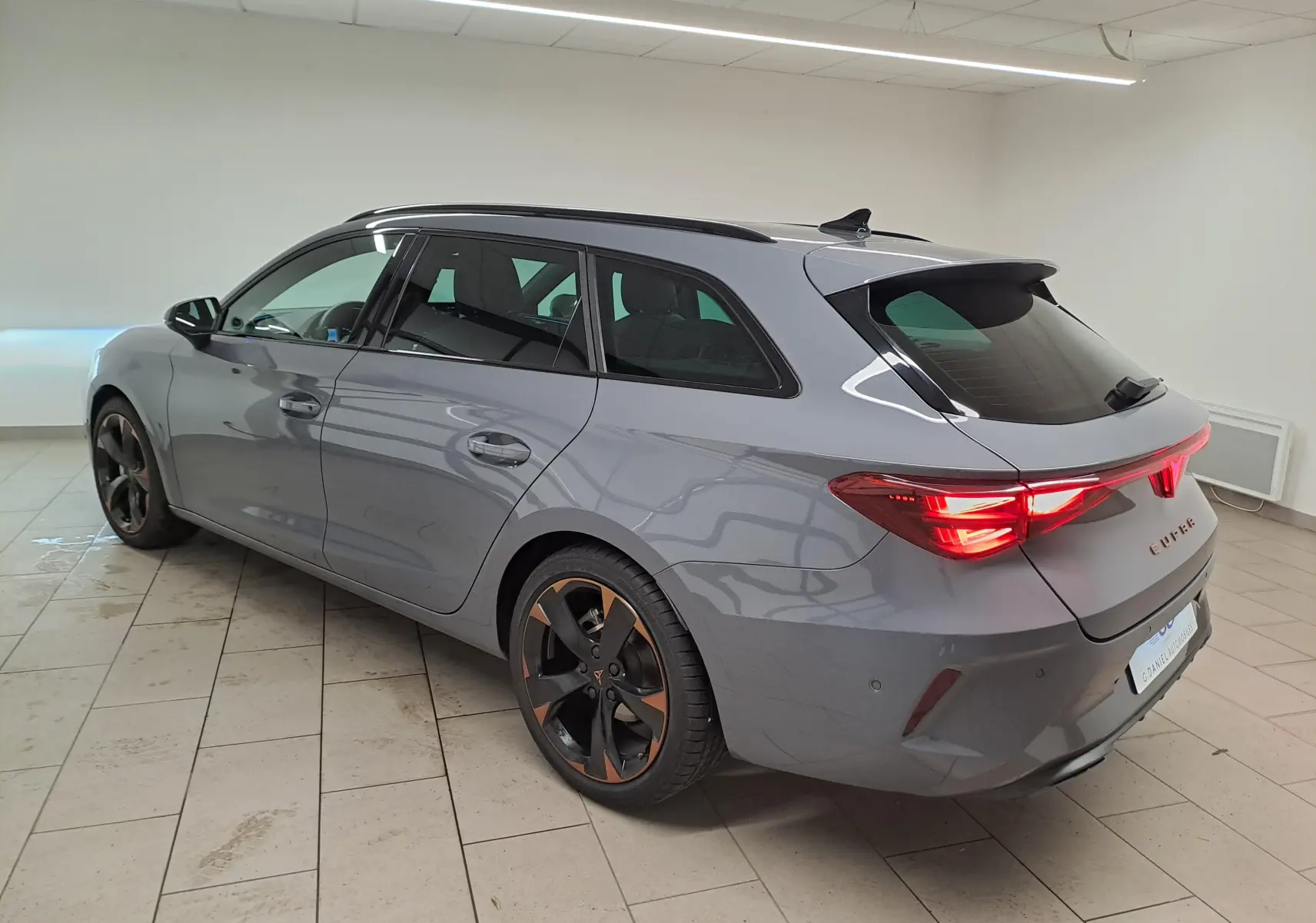 Vue 3/4 arrière droite d'une CUPRA Leon ST 2025 gris Graphène avec jantes cuivrées et toit ouvrant panoramique.