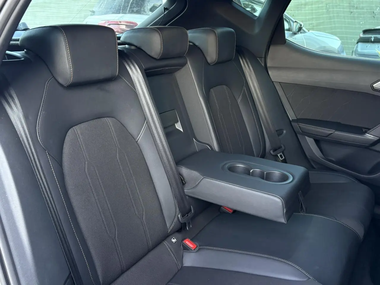 Vue intérieure côté droit des sièges arrière noirs bimatière avec accoudoir central et porte-gobelets du CUPRA Leon 2025.