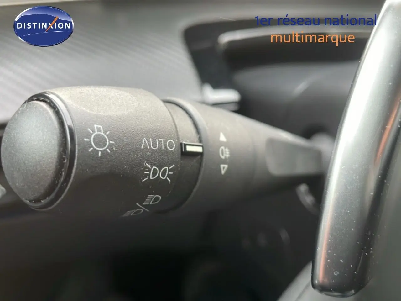 Gros plan sur la commande des phares à gauche du volant dans l’habitacle noir d’une Peugeot 508 SW noire.