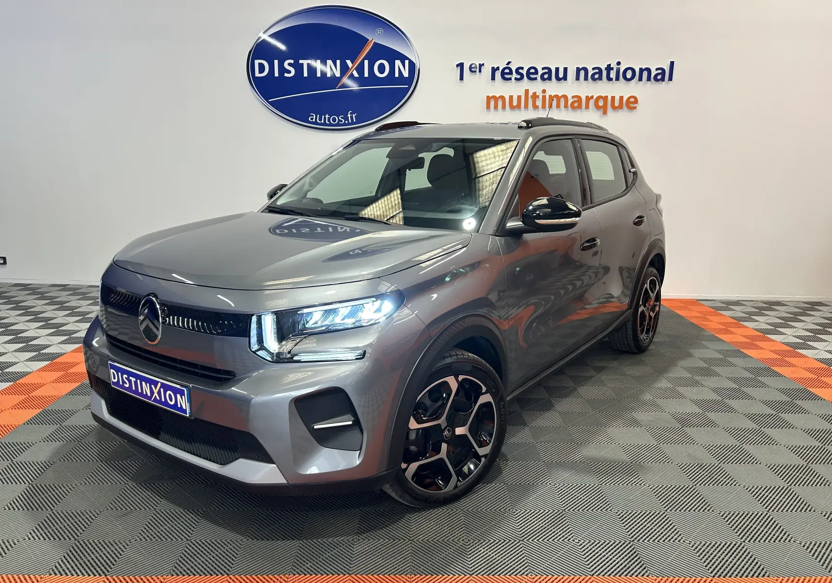 Citroën C3 Turbo 100 PLUS gris Artense en 3/4 avant droit, avec jantes bi-ton et phares LED allumés.