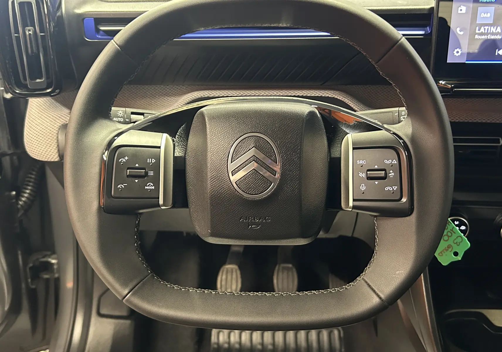 Vue rapprochée du volant cuir noir de la Citroën C3 2025 avec commandes intégrées et logo central argenté.