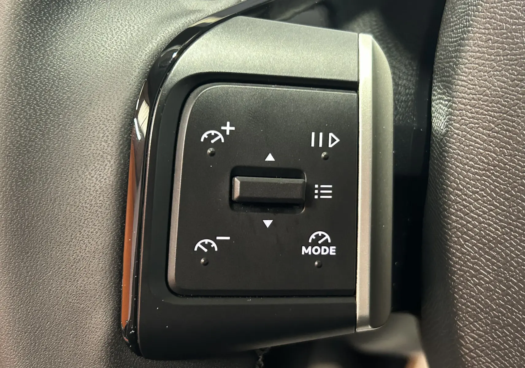 Gros plan sur les commandes au volant du Citroën C3 Turbo 100 Plus, boutons noirs avec symboles blancs, intérieur gris.
