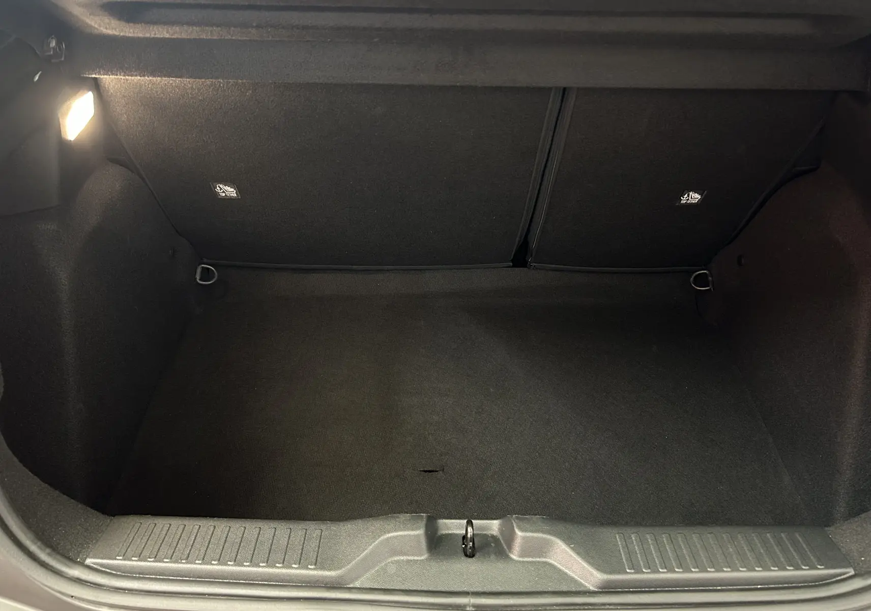 Coffre ouvert de la Citroën C3 gris Artense, vue intérieure montrant l'espace de rangement et l'éclairage à gauche.