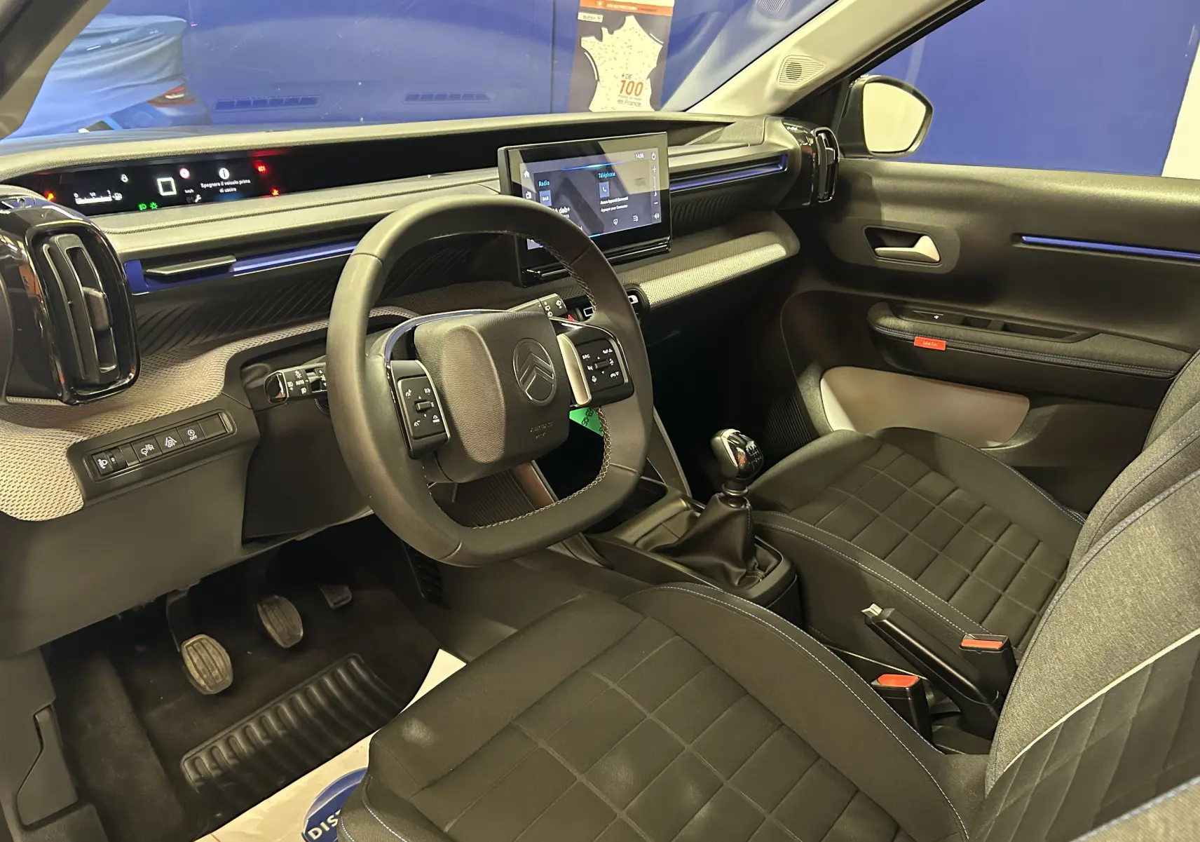 Vue intérieure côté conducteur de la Citroën C3 Turbo 100 Plus gris Artense, avec volant cuir et écran tactile central.