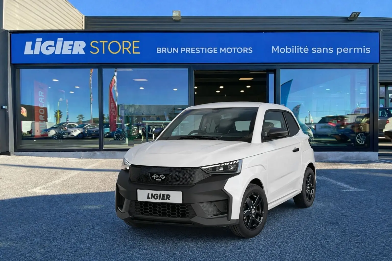 Vue 3/4 avant d'une Ligier JS50 Select Revo D+ blanc glacier avec calandre noire et jantes noires devant un showroom.