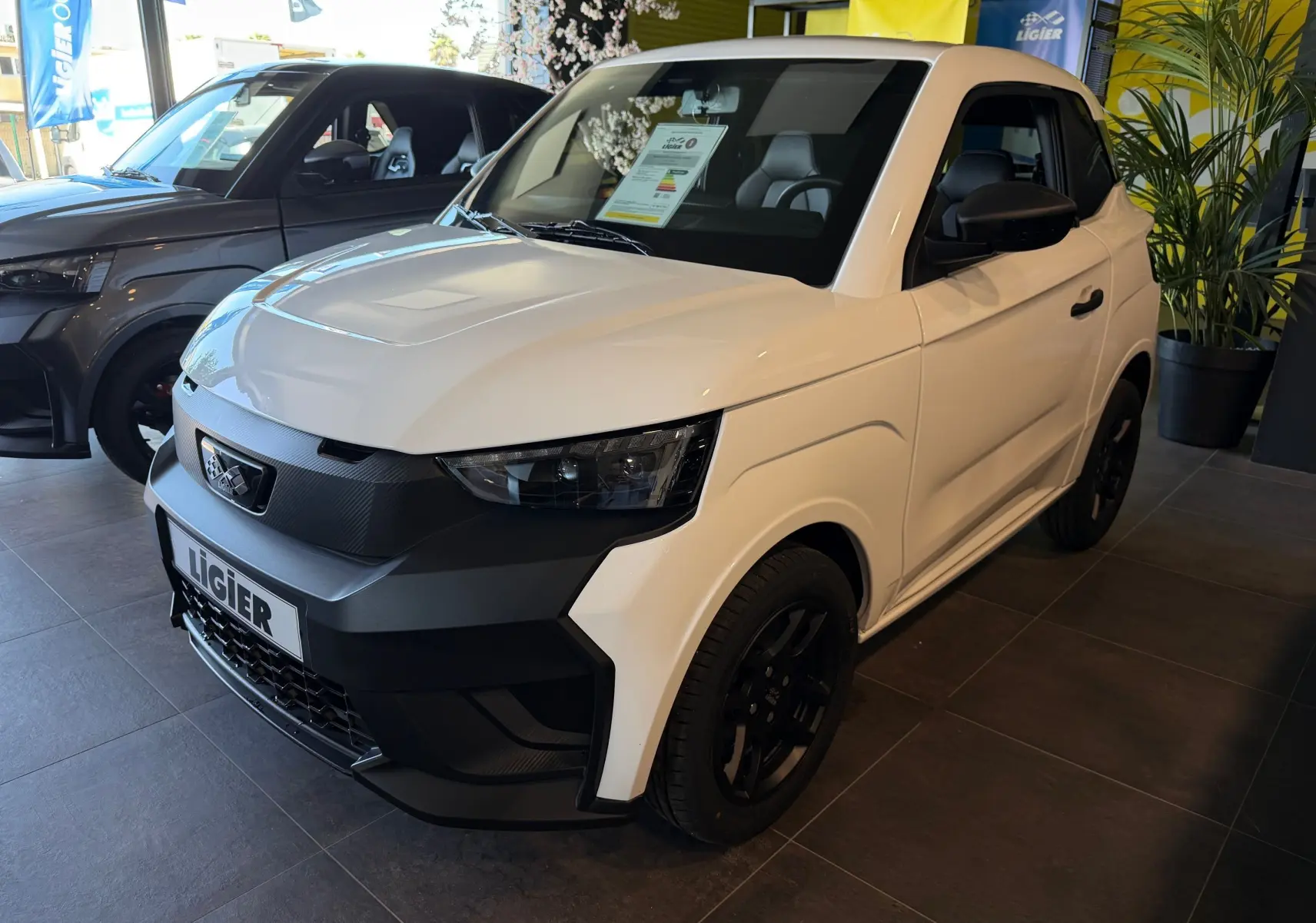 Vue 3/4 avant droite d'une Ligier JS50 Select Revo D+ blanc glacier avec détails noirs contrastants en showroom.