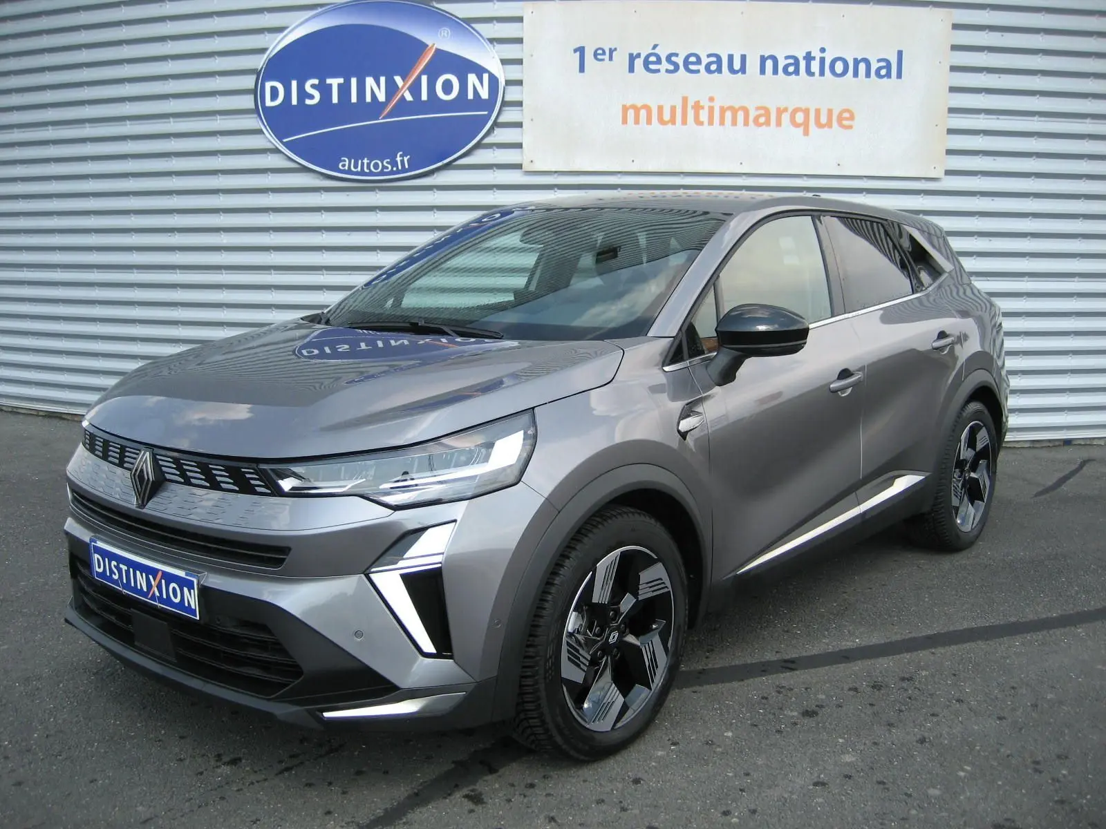 Renault Symbioz gris cassiopée en 3/4 avant droit, SUV hybride avec calandre moderne et jantes bicolores distinctives.
