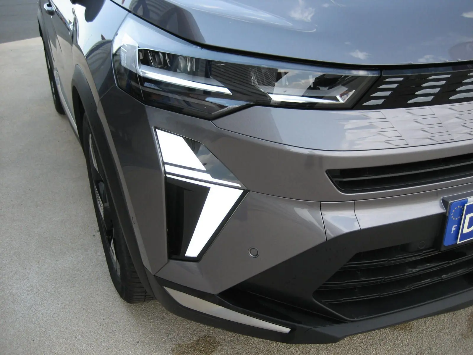 Gros plan sur l'avant droit gris cassiopée du Renault Symbioz 2025, mettant en valeur ses feux LED distinctifs et la calandre moderne.