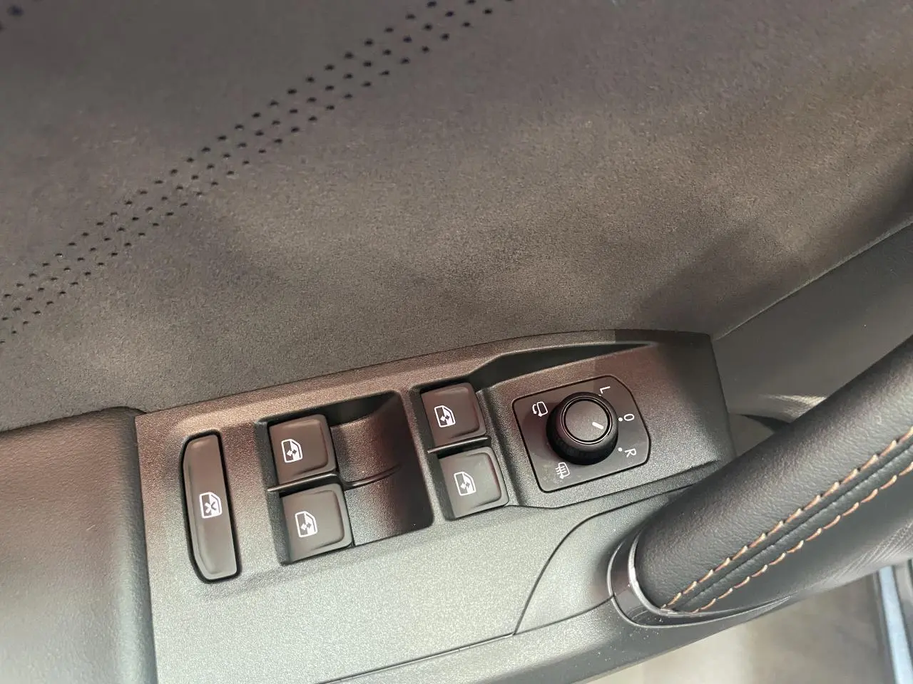 Détail des commandes de lève-vitres et réglage des rétroviseurs côté conducteur d’une CUPRA Leon gris intérieur suédine.