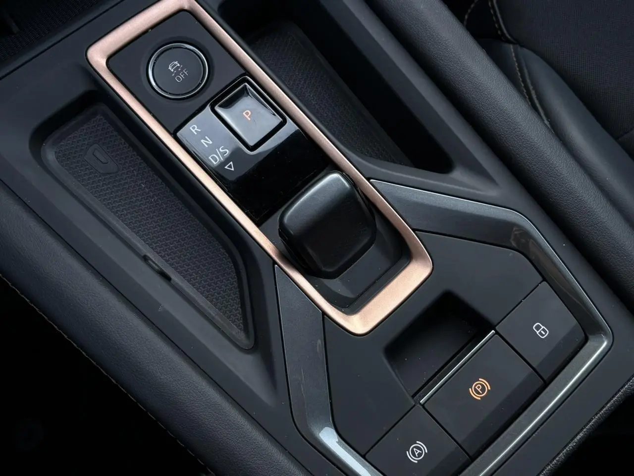 Gros plan sur la console centrale noire avec levier de vitesses automatique et cadre cuivré dans une CUPRA Leon blanche.