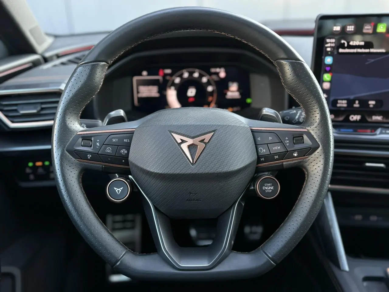 Vue rapprochée du volant cuir perforé noir avec logo CUPRA et commandes multifonctions du Leon 2025.