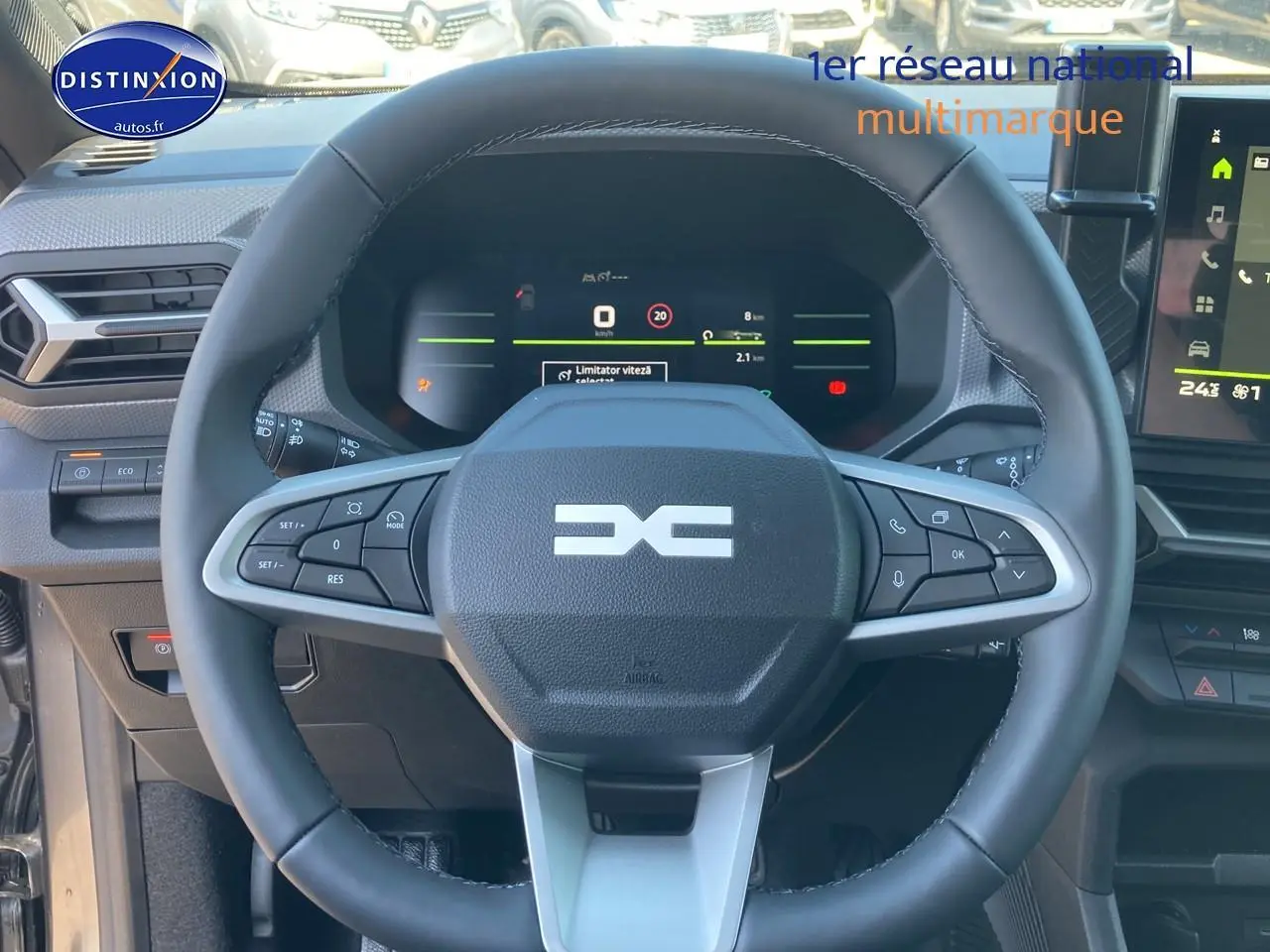 Vue rapprochée du volant multifonction noir du Dacia Duster 1.2 mild hybrid 140 Journey avec tableau de bord numérique allumé.