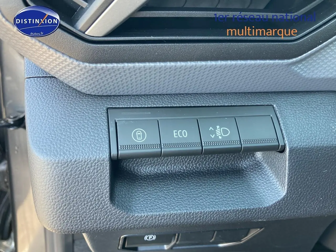 Gros plan sur les commandes ECO et réglage des phares du tableau de bord du Dacia Duster gris schiste 2026.